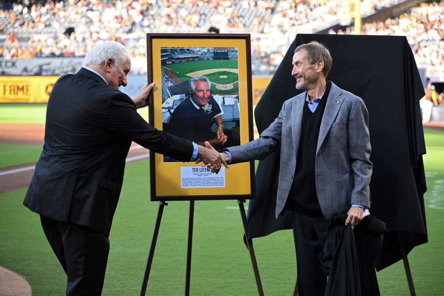 San Diego Padres chairman Peter Seidler, right, shakes hands with Padres former radio announcer and team ambassador Ted Leitner