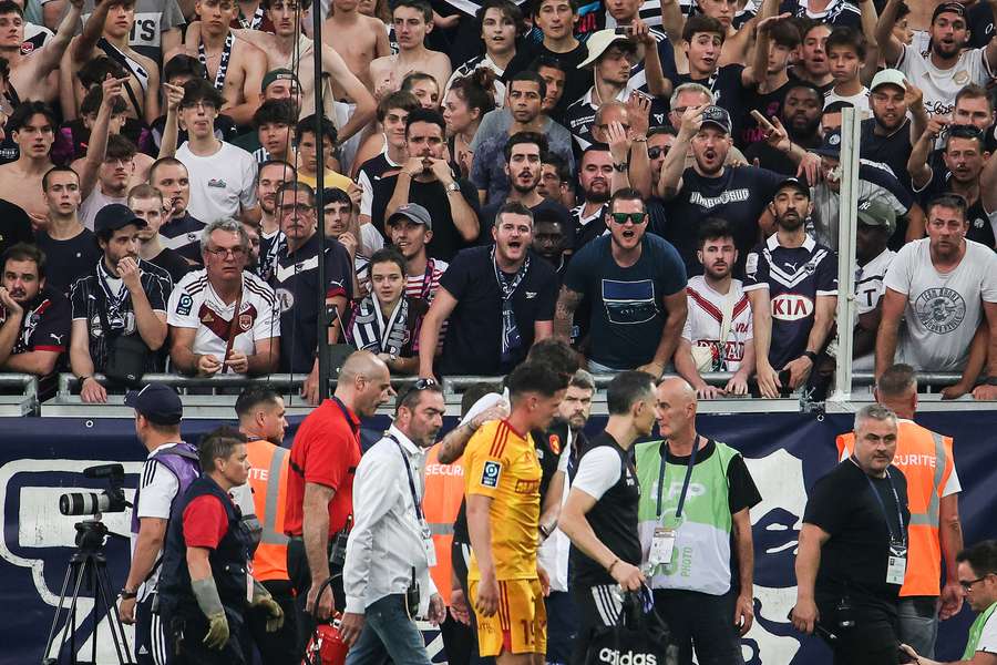 Bordeaux supporters react as Rodez' French midfielder Lucas Buades (C) walks off the pitch after being hit by a projectile