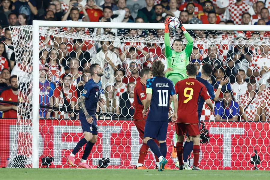 Croatia goalkeeper Dominik Livakovic (C) jumps to catch the ball