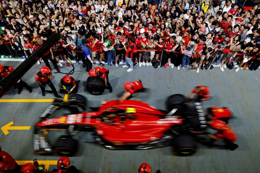 Charles Leclerc signs autographs for fans as Carlos Sainz Jr.'s car is seen in the pits in Singapore