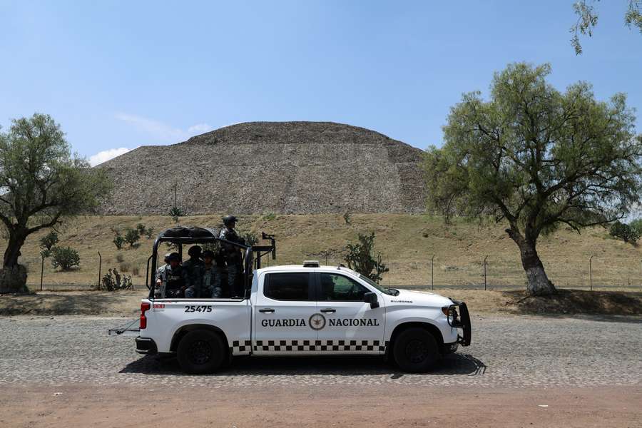 Members of the National Guard stand on a vehicle with the Pyramid of the Moon in the background