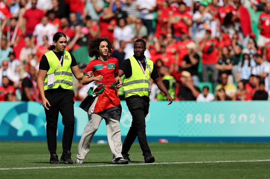 A pitch invader is detained by stewards during the match