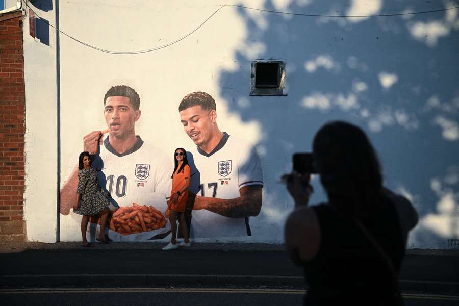 Dois fãs posam em frente a um mural de Judd Bellingham e Morgan Rogers