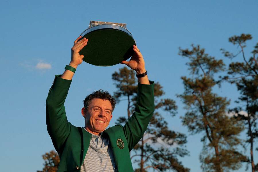 Rory McIlroy celebrates with his green jacket and the trophy after winning The Masters