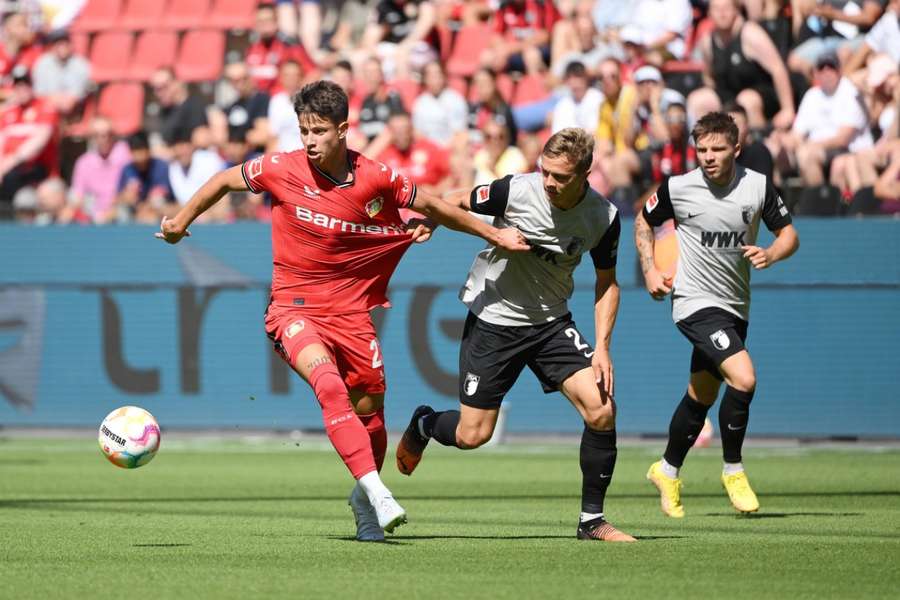 Adam Hložek v souboji s Robertem Gumnym v zápase Leverkusen - Augsburg.