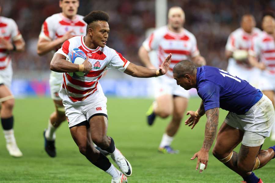 Japan's right wing Kotaro Matsushima (L) hands off a tackle from Samoa's right wing Ed Fidow (R) 