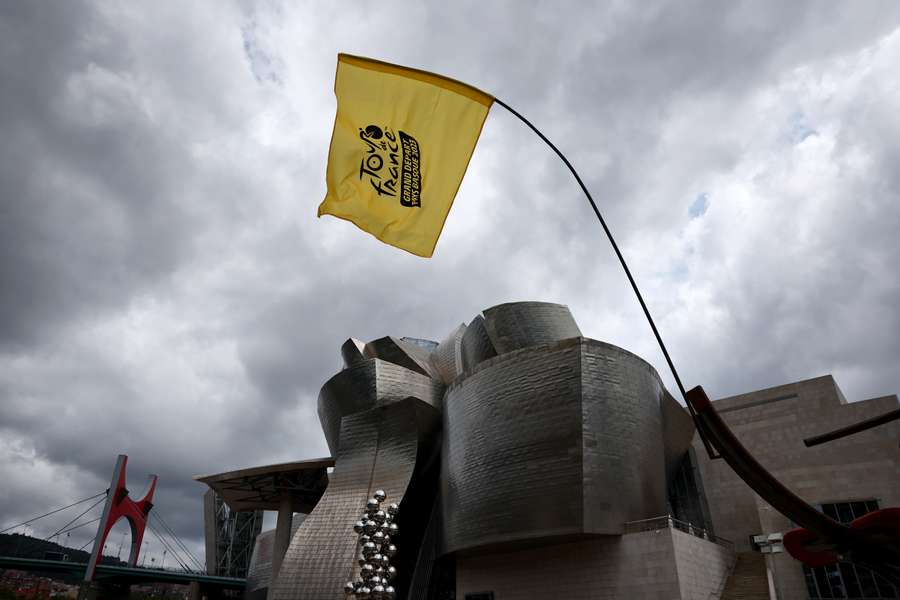 Vlajka Tour de France majestátně vlaje v popředí Guggenheimova muzea v Bilbau.