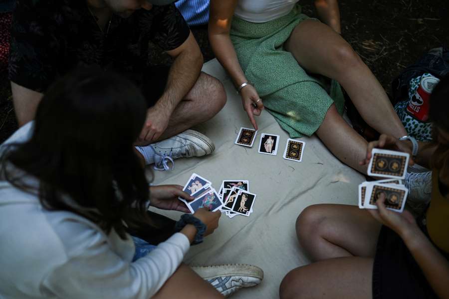 As pessoas jogam às cartas enquanto fazem fila à porta do All England Tennis Club