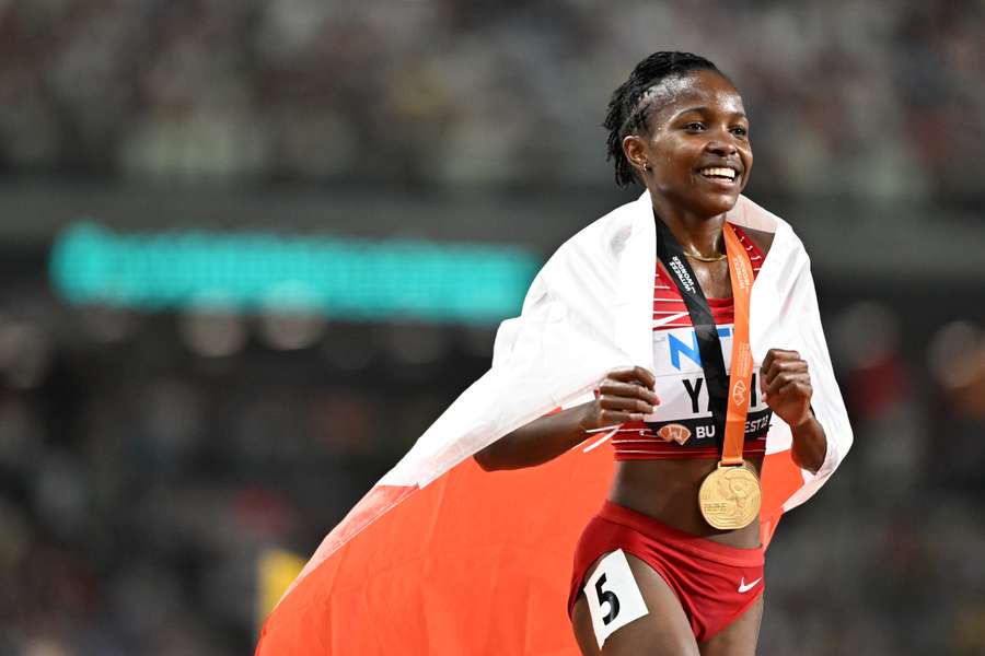 Winfred Mutile Yavi celebrates with her national flag after winning the women's 3000m steeplechase final