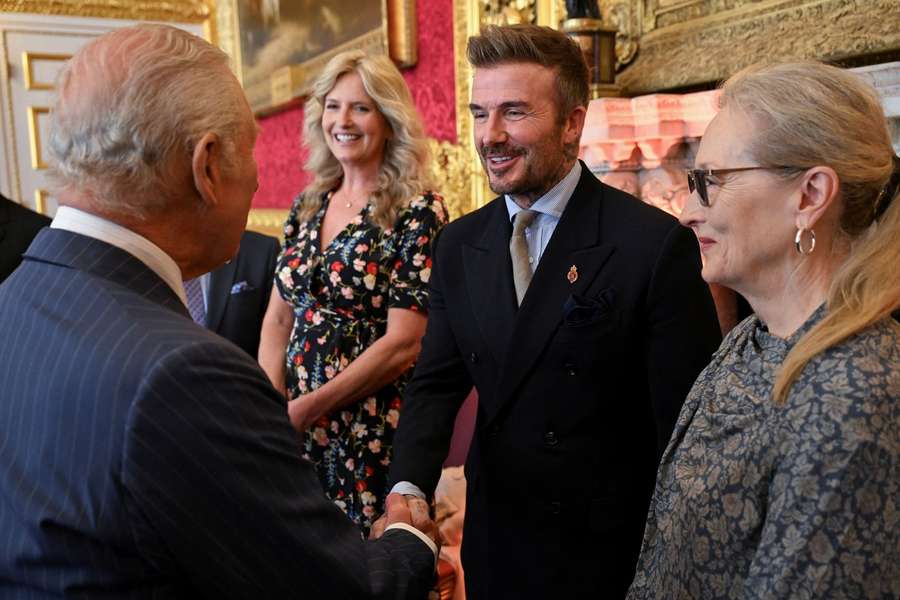 Kráľ Karol III. podáva ruku Davidovi Beckhamovi.