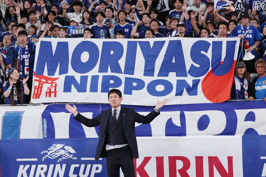 Japan's manager Hajime Moriyasu poses with a banner during the game against New Zealand.