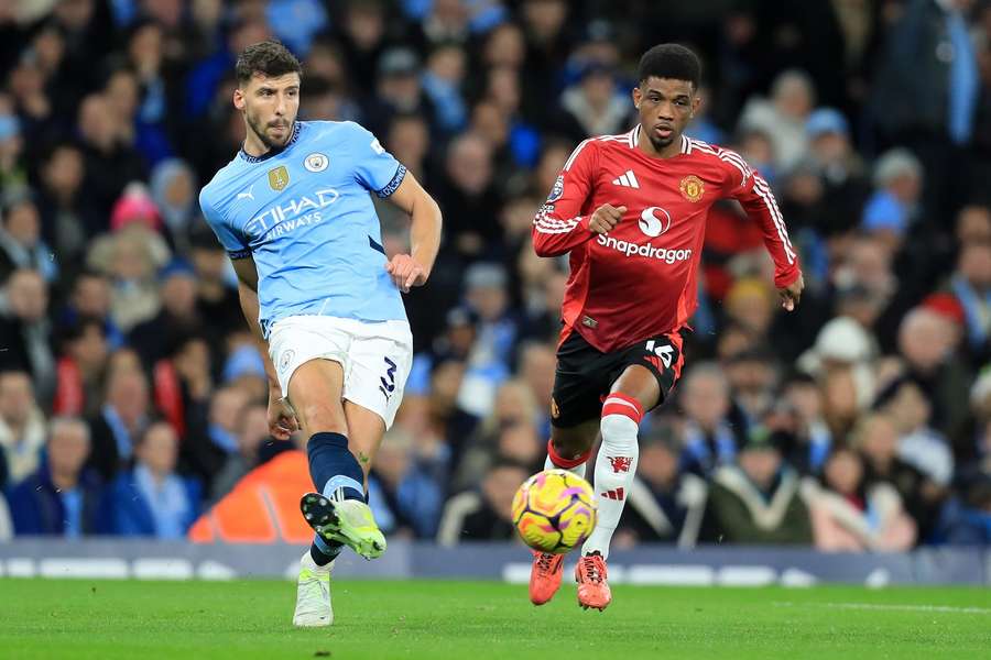 Man City's Ruben Dias passes the ball under pressure from Man Utd's Amad Diallo