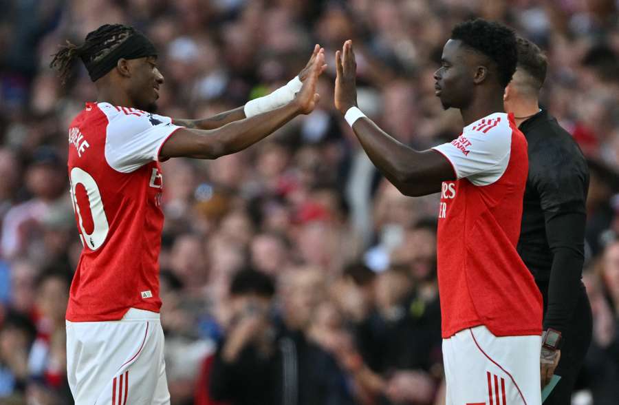 Noni Madueke taps hands with Bukayo Saka as he comes off.