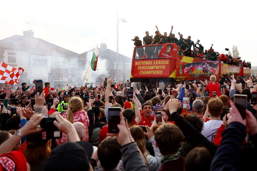 Os torcedores comemoram com os jogadores do Wrexham no ônibus durante o desfile da vitória