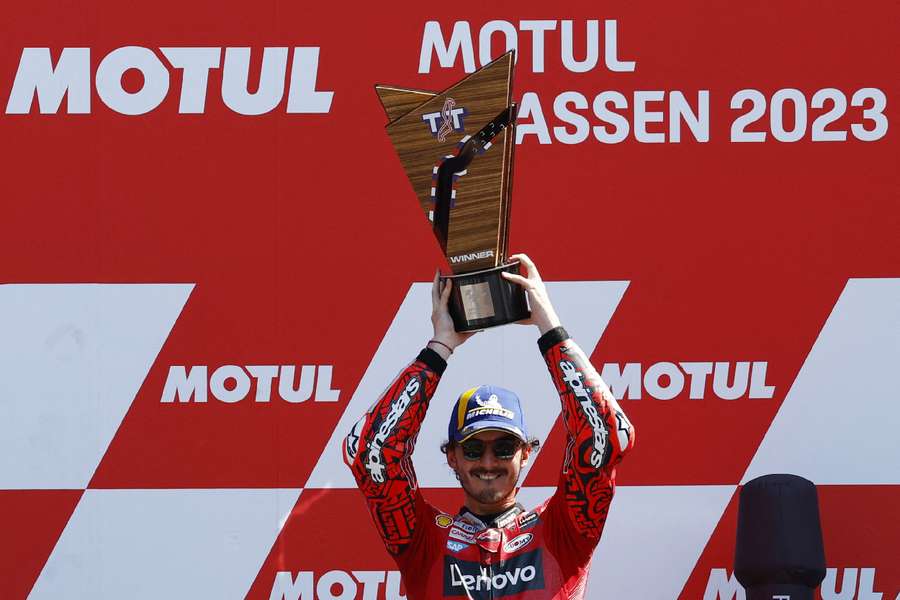 Francesco Bagnaia celebrates with the trophy on the podium after winning