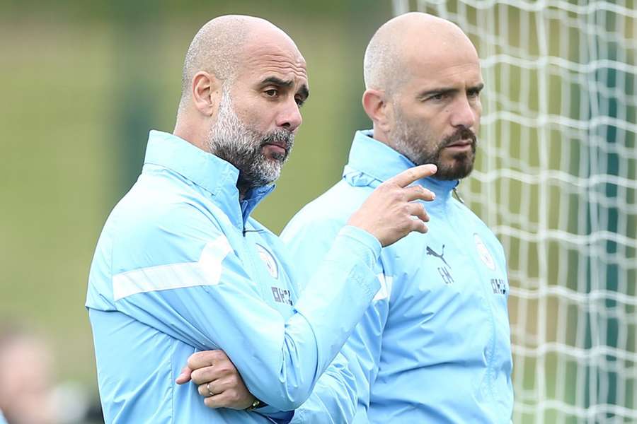 Manchester City manager Pep Guardiola (L) speaks to assistant manager Enzo Maresca during a training session