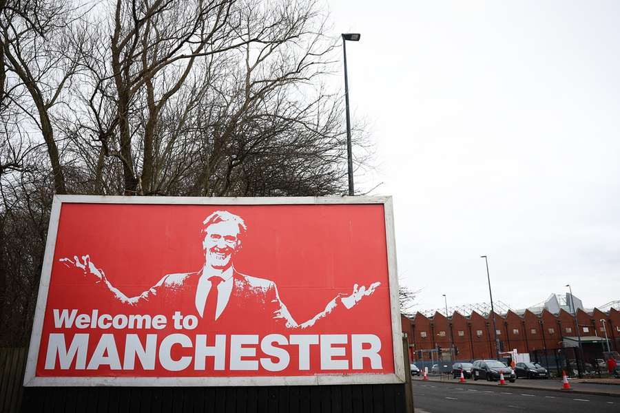 Een billboard met daarop Jim Ratcliffe nabij Old Trafford