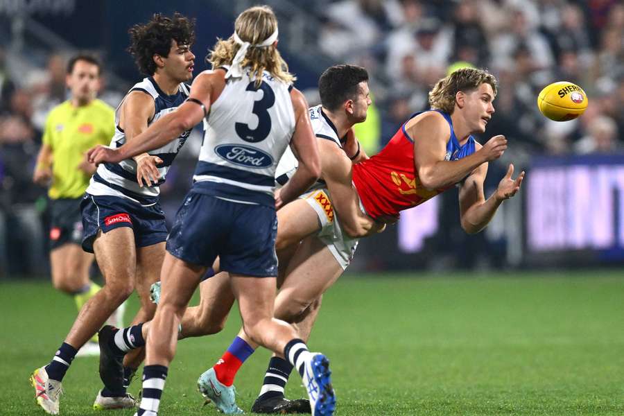 Brisbane's Will Ashcroft handballs whilst being tackled against Geelong in Round 15.
