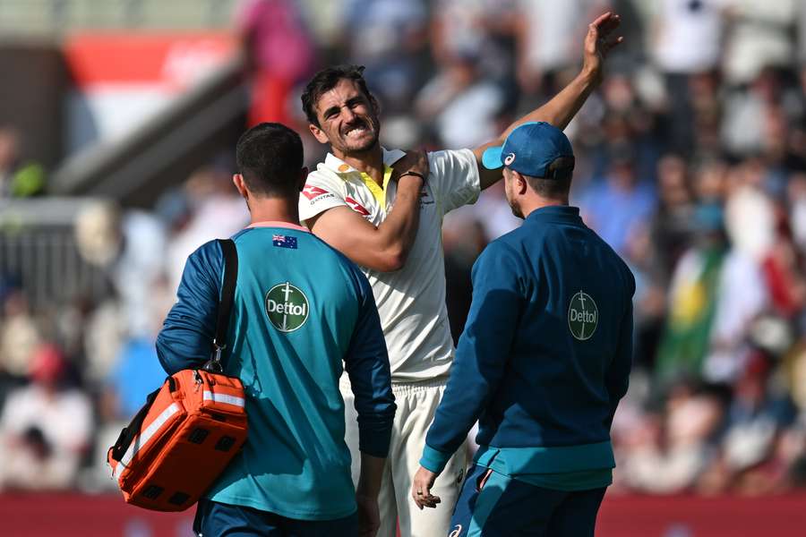 Australia's Mitchell Starc (C) receives medical attention after hurting his shoulder