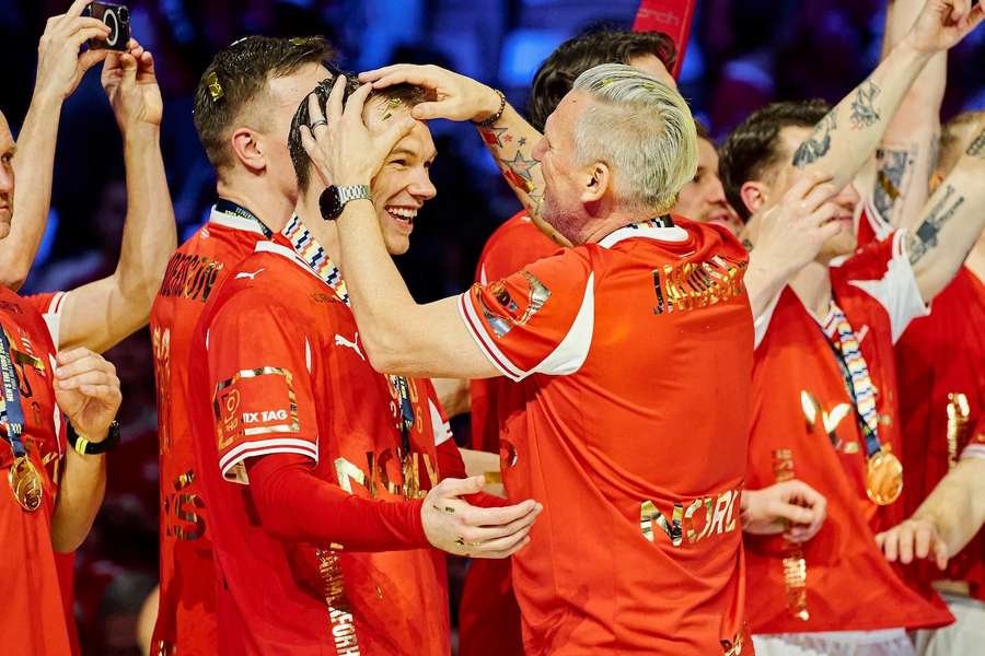 Mathias Gidsel wird nach dem gewonnenen Finale von Dänemarks Nationaltrainer Nikolaj Jacobsen geherzt.