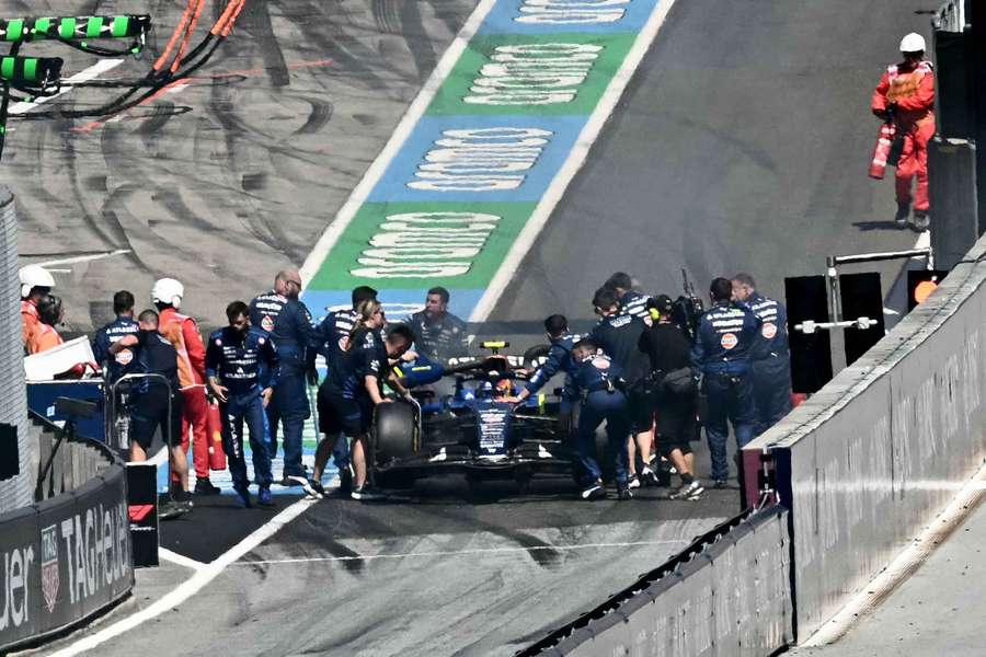 Marshalls and crew members attend to Sainz's car