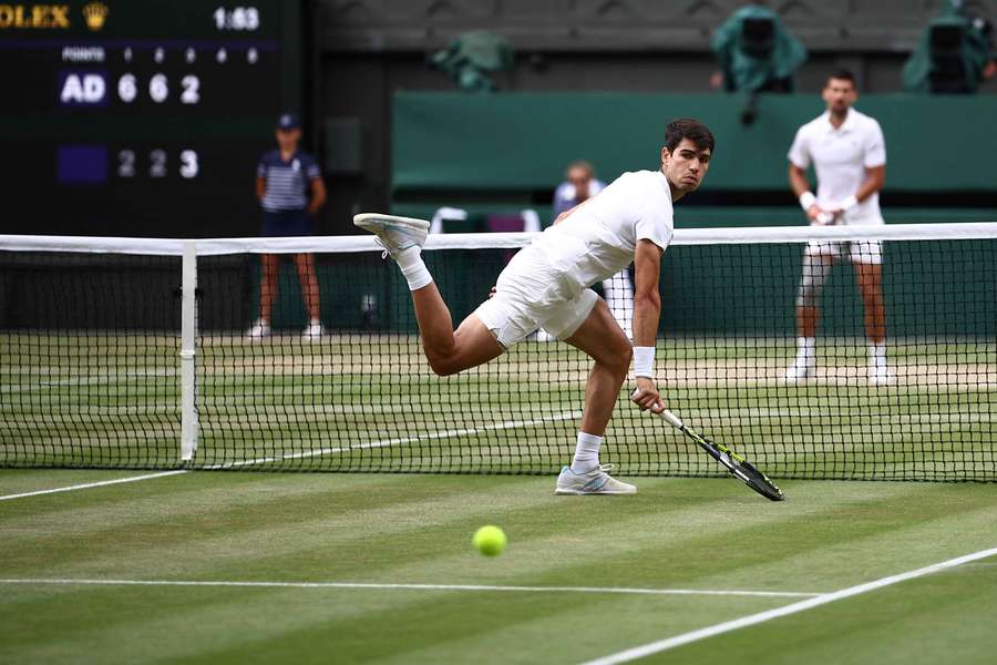 El español Carlos Alcaraz (delante) observa la pelota tras fallar una devolución del serbio Novak Djokovic durante la final individual masculina. 