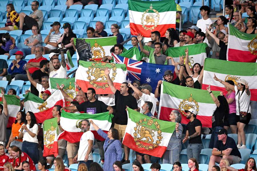Aficionados de Irán exhiben sus banderas en un partido de fútbol