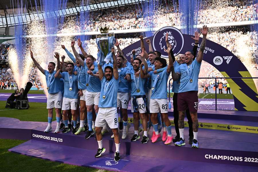 O meio-campista alemão do Manchester City, Ilkay Gundogan, levanta o troféu enquanto os jogadores do Manchester City comemoram a conquista do título na cerimônia de apresentação