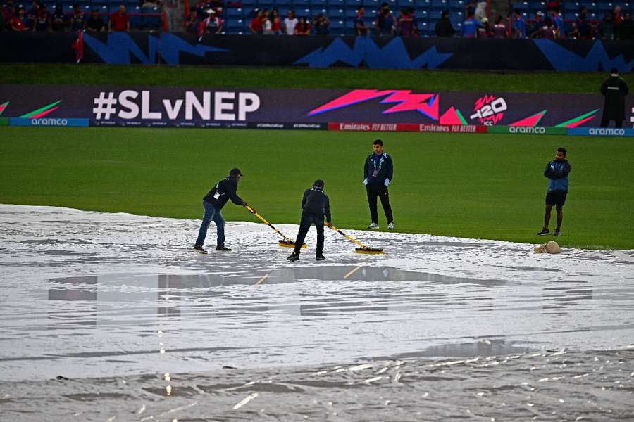 Match officials wipe water from the pitch