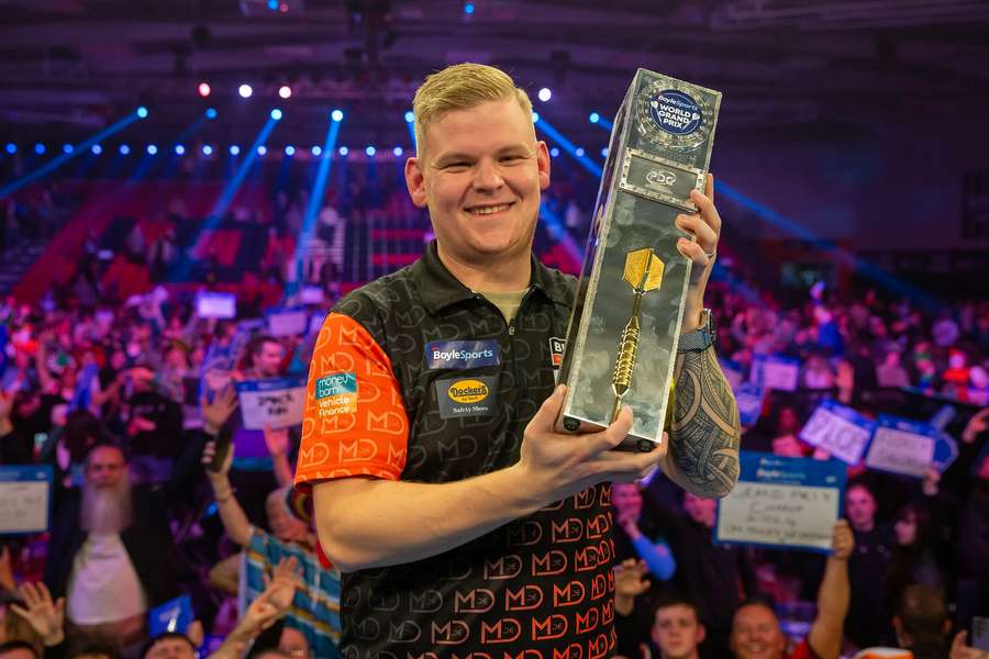 Mike De Decker lifts the 2024 World Grand Prix trophy after beating Luke Humphries in the final
