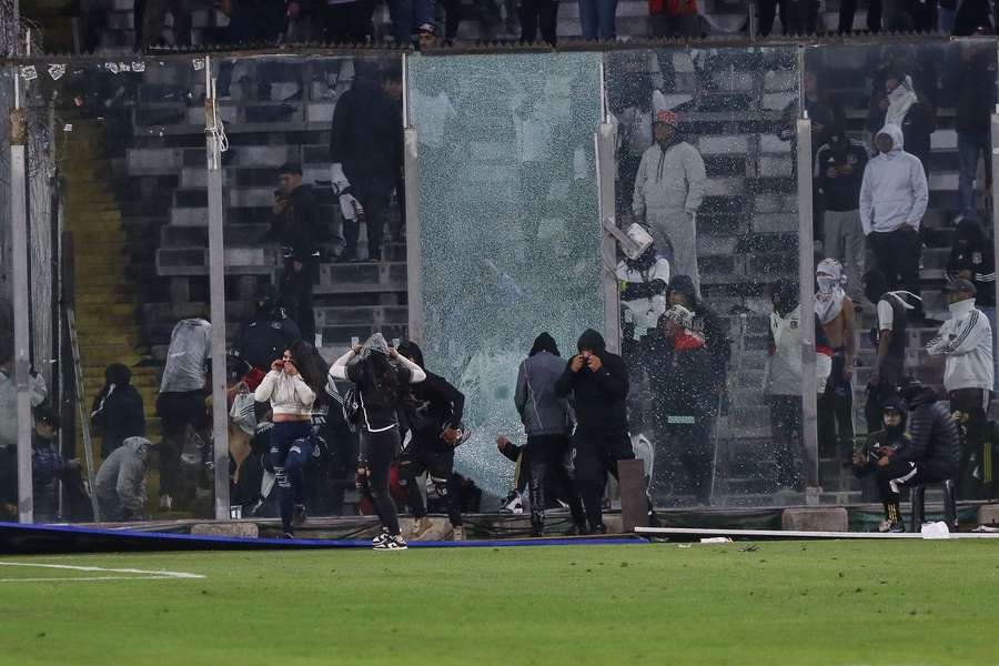 Colo Colo supporters enter the field to suspend the game in protest after the deaths of two fans