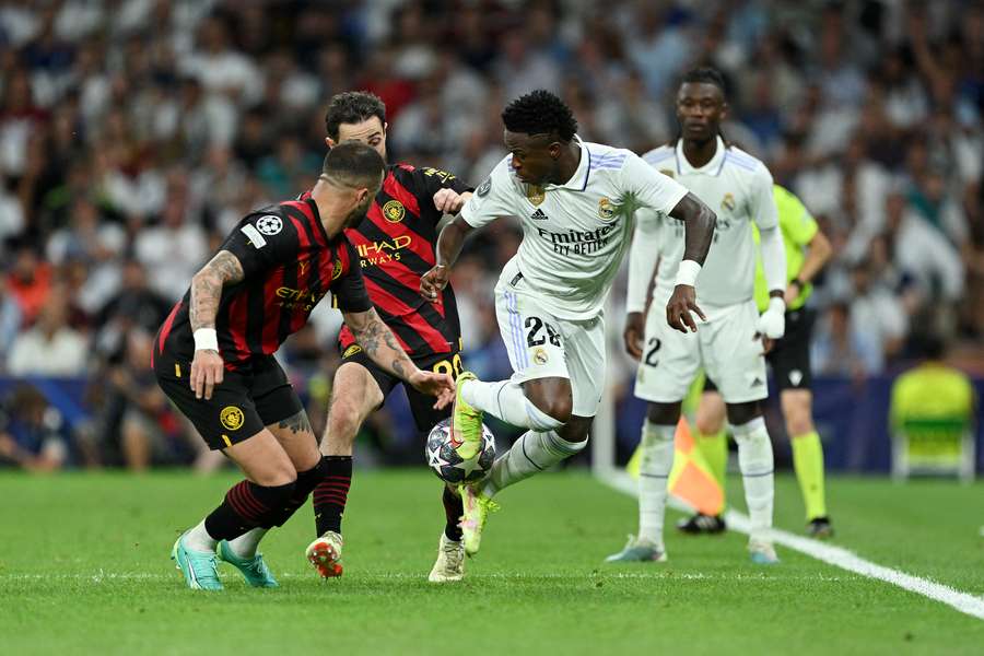 Vinicius Junior of Real Madrid is challenged by Bernardo Silva and Kyle Walker of Manchester City