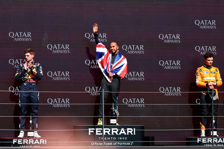 Lando Norris on the podium alongside Max Verstappen, left, and Lewis Hamilton, centre