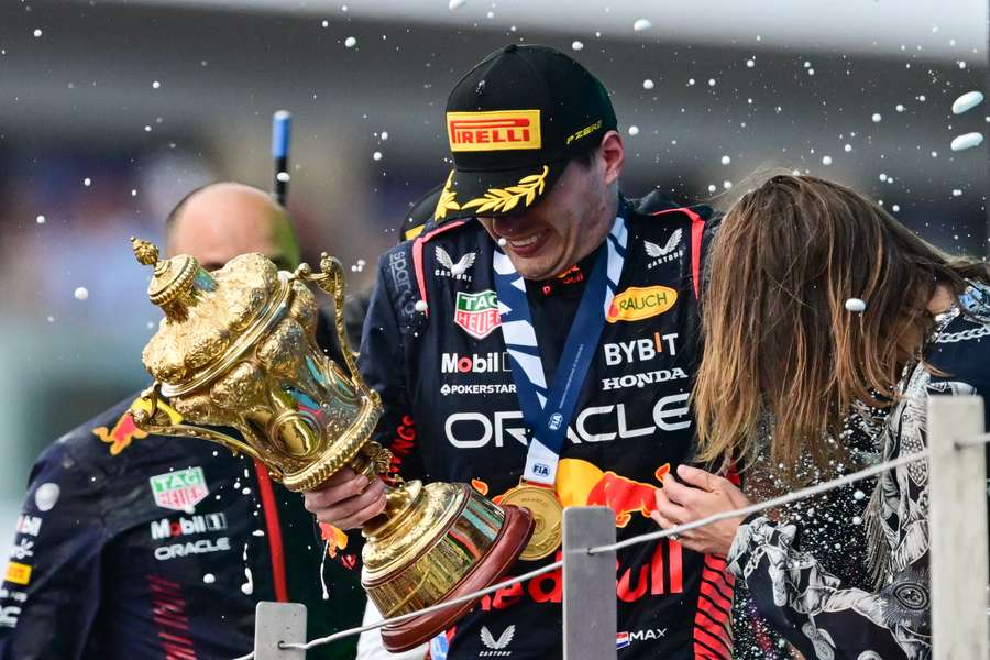 Winner Red Bull Racing's Dutch driver Max Verstappen holding the trophy reacts as second-placed McLaren's British driver Lando Norris sprays champagne