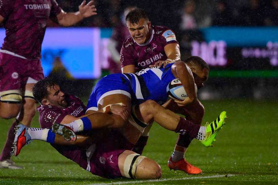 Ollie Lawrence of Bath is tackled by Sam Dugdale and Joe Carpenter of Sale