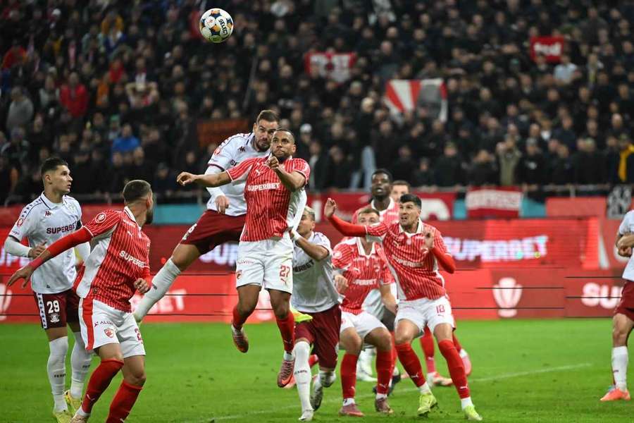 Maxime Sivis (centru) câștigă un duel aerian în fața lui Elvir Koljic, în timpul derby-ului Dinamo - Rapid