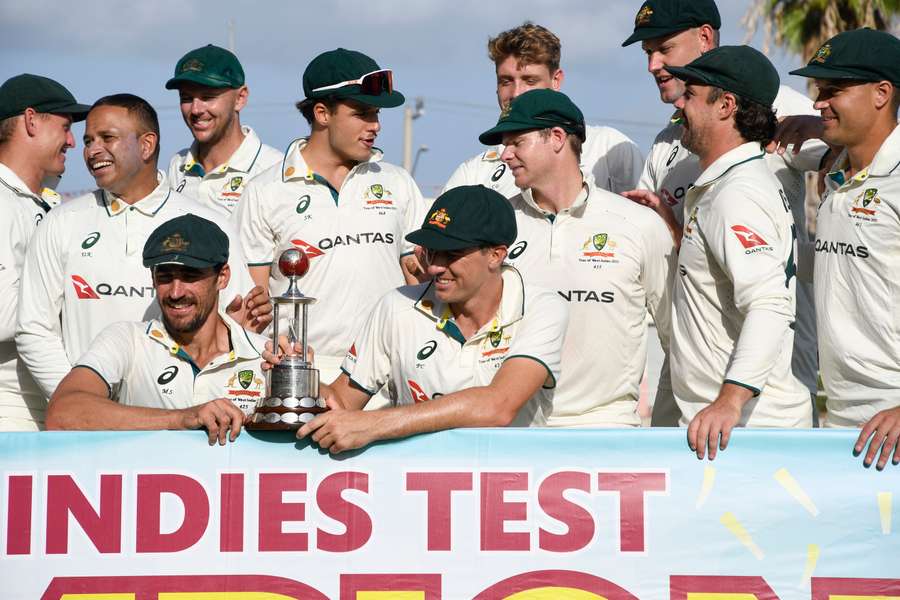 Mitchell Starc (left) and Pat Cummins, and teammates of Australia, pose with the trophy after winning the third Test against West Indies