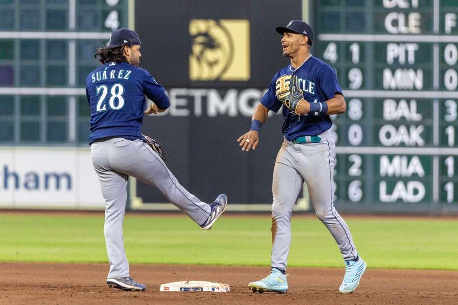 El tercera base de los Marineros de Seattle Eugenio Suárez y el jardinero central Julio Rodríguez celebran la derrota de los Astros de Houston.