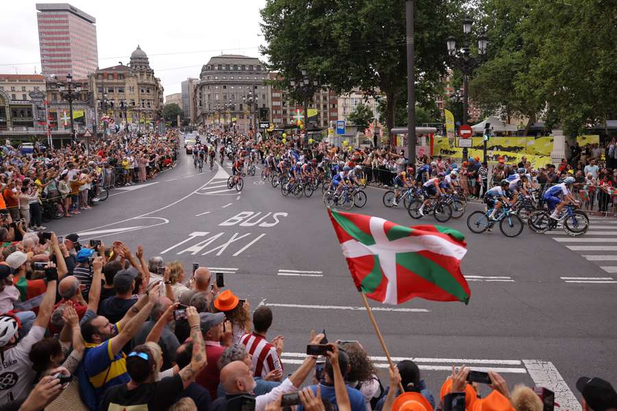 A spectator waves a Basque regional flag as the pack of riders cycles at the start of the first stage of the 110th edition of the Tour de France