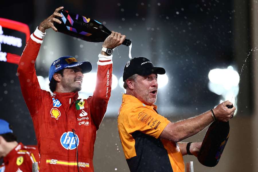 Carlos Sainz Jr. celebrates on the podium after finishing second with McLaren chief executive Zak Brown