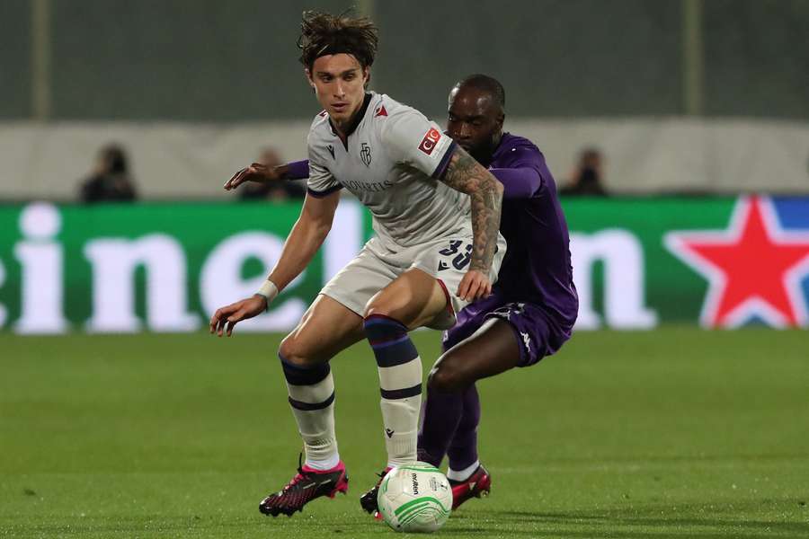 Calafiori, de blanco, protege un balón ante Ikone, jugador de la Fiorentina