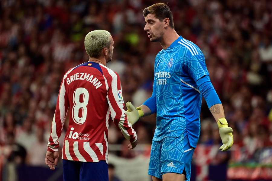 Atletico Madrid's French forward Antoine Griezmann talks with Real Madrid's Belgian goalkeeper Thibaut Courtois