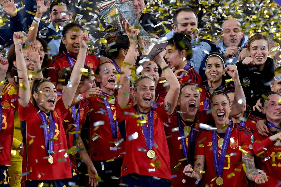Spain's midfielder #11 Alexia Putellas lifts the trophy as her teammates celebrate winning