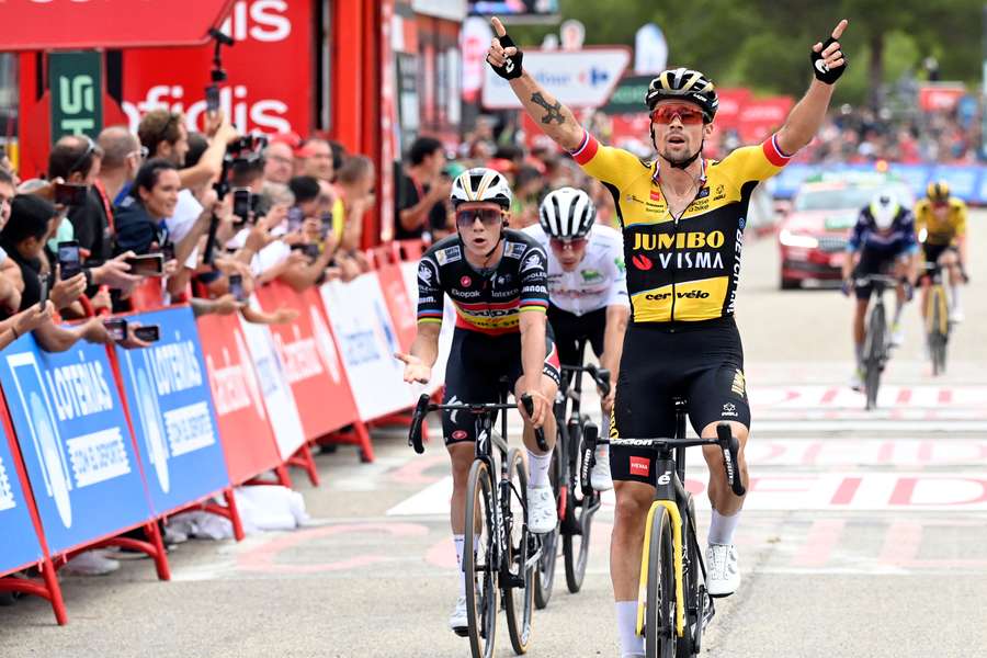 Roglic levanta los brazos como ganador de etapa ante Evenepoel en la etapa 8, en Xorret de Cati